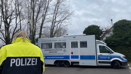 Das Präventionsmobil des Landeskriminalamt steht auf dem Hof, eine Polizistin in Uniform steht mit dem Rücken zum Betrachter davor.